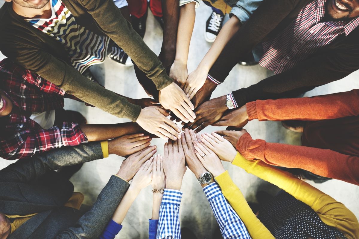 a group of people place their hands into the centre of their circle