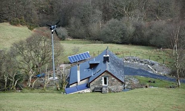 Off-the-grid house with solar panels and a wind turbine.