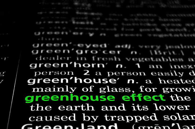 The phrase, "greenhouse effect" is highlighted green on the page of a dictionary.